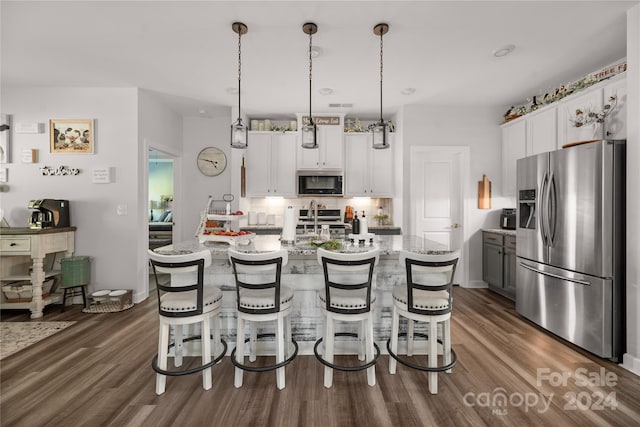 kitchen with dark hardwood / wood-style floors, a kitchen island with sink, stainless steel appliances, and white cabinets