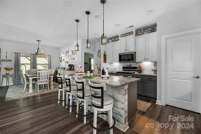 kitchen featuring appliances with stainless steel finishes, pendant lighting, gray cabinets, and dark wood-type flooring