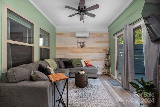 living room with a wall unit AC, ceiling fan, crown molding, light hardwood / wood-style flooring, and wood walls