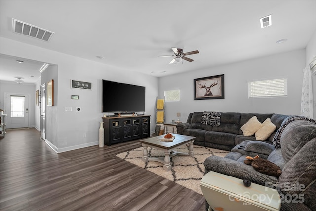 living area with wood finished floors, visible vents, a ceiling fan, and baseboards