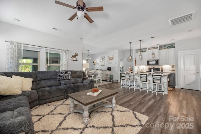 living room featuring a ceiling fan, visible vents, and dark wood-type flooring