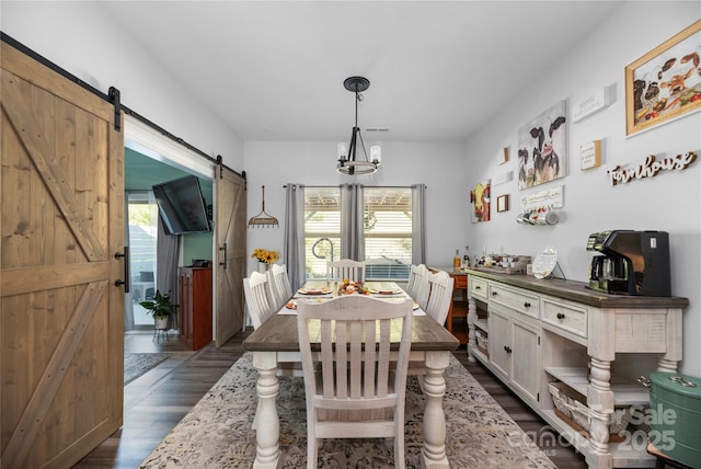 dining area with a barn door, dark wood finished floors, plenty of natural light, and a notable chandelier