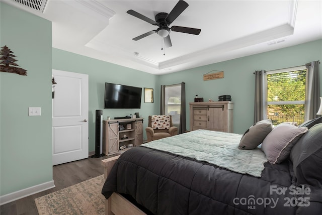 bedroom featuring visible vents, a tray ceiling, and multiple windows