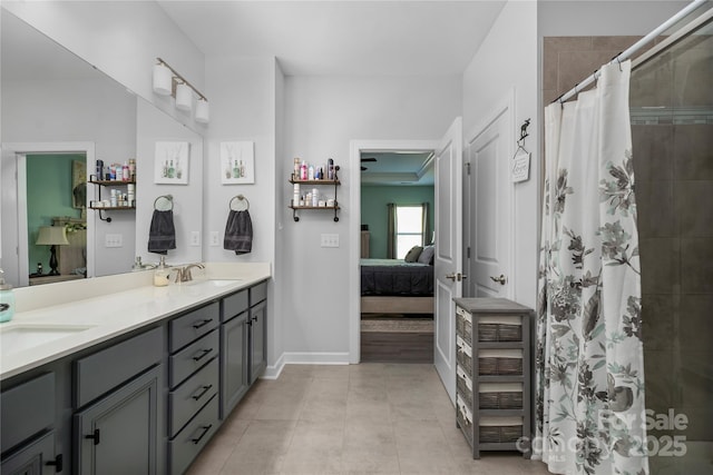 full bath featuring ensuite bathroom, double vanity, a tile shower, baseboards, and tile patterned flooring