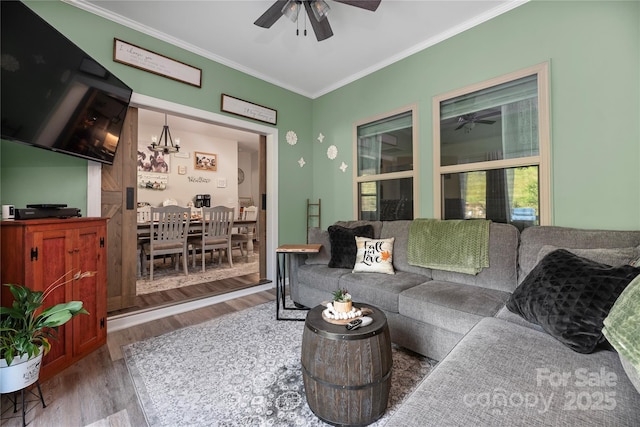living area featuring crown molding, wood finished floors, and ceiling fan with notable chandelier