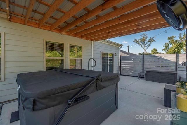 view of patio / terrace featuring fence and a hot tub