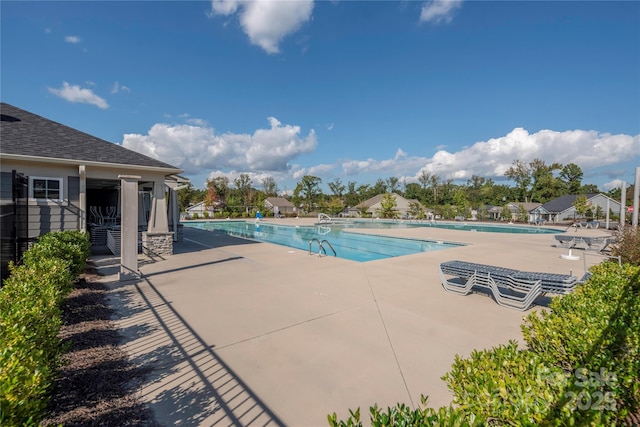 community pool with a water slide, fence, and a patio area