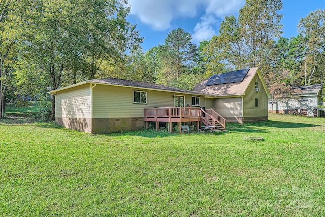 rear view of house featuring a wooden deck and a lawn