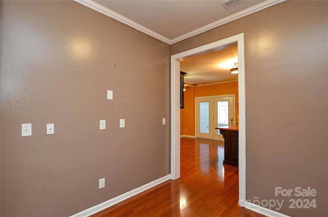 corridor with ornamental molding, hardwood / wood-style flooring, and french doors