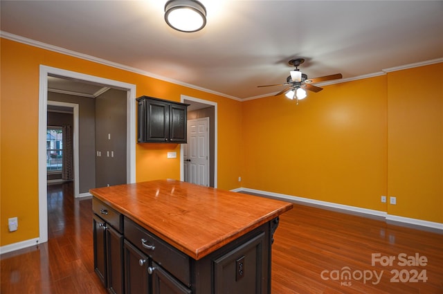 kitchen with ceiling fan, crown molding, dark wood-type flooring, and a center island