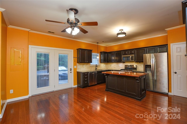 kitchen with stainless steel appliances, crown molding, decorative light fixtures, and hardwood / wood-style flooring