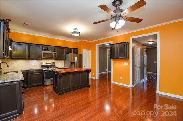 kitchen with light stone counters, sink, a kitchen island, appliances with stainless steel finishes, and hardwood / wood-style floors