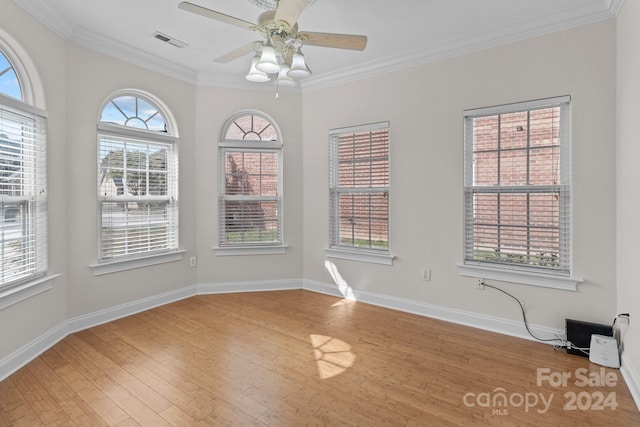 unfurnished room featuring a healthy amount of sunlight, crown molding, and wood-type flooring