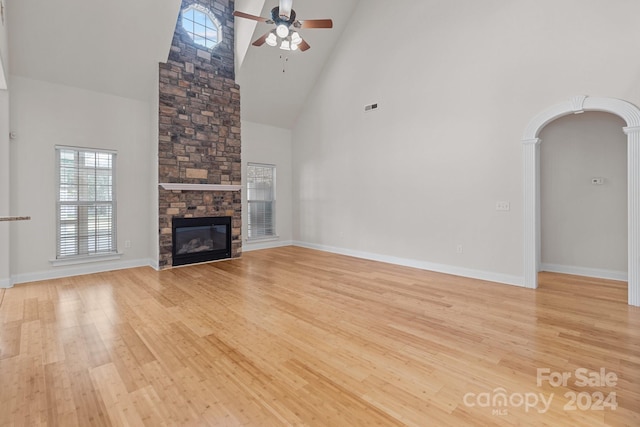 unfurnished living room with a fireplace, ceiling fan, light hardwood / wood-style flooring, and high vaulted ceiling