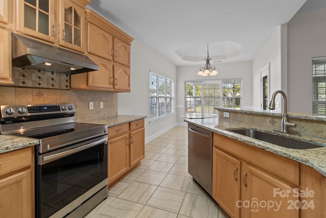 kitchen with light stone counters, sink, a chandelier, appliances with stainless steel finishes, and decorative backsplash