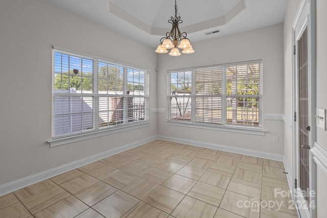 unfurnished dining area featuring visible vents, baseboards, plenty of natural light, a notable chandelier, and a tray ceiling