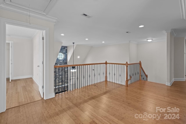 empty room with ornamental molding, visible vents, attic access, and hardwood / wood-style floors
