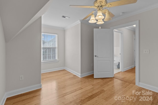empty room with baseboards, crown molding, light wood-style floors, visible vents, and ceiling fan