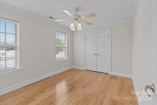 unfurnished bedroom featuring crown molding, a closet, light wood finished floors, and visible vents