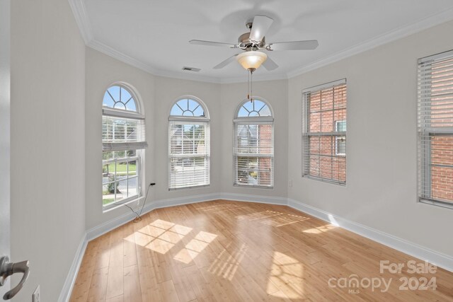 spare room featuring light wood-type flooring, a healthy amount of sunlight, crown molding, and ceiling fan