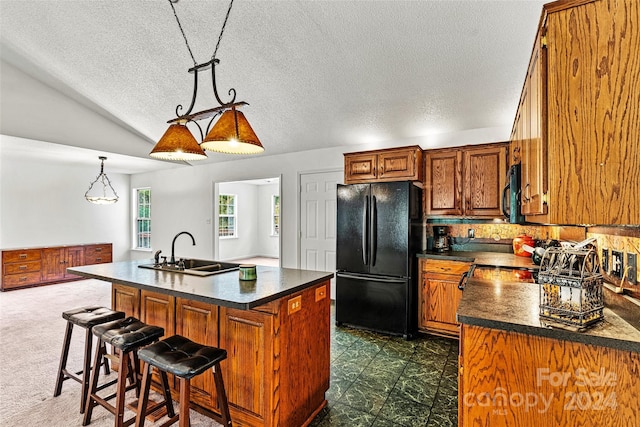 kitchen with black appliances, sink, a center island with sink, and a textured ceiling