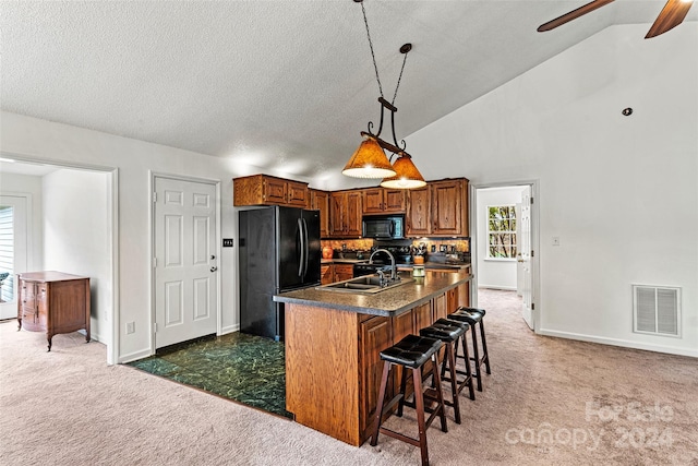 kitchen with an island with sink, dark colored carpet, black appliances, and lofted ceiling