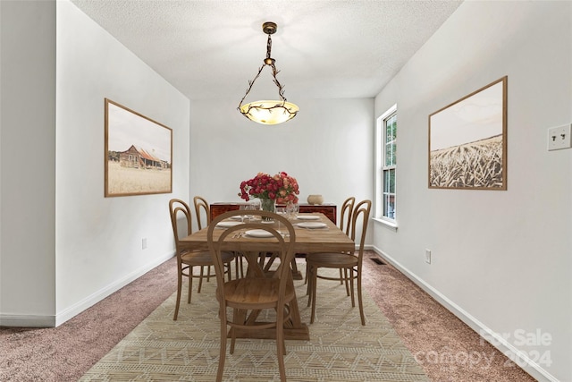 carpeted dining room featuring a textured ceiling