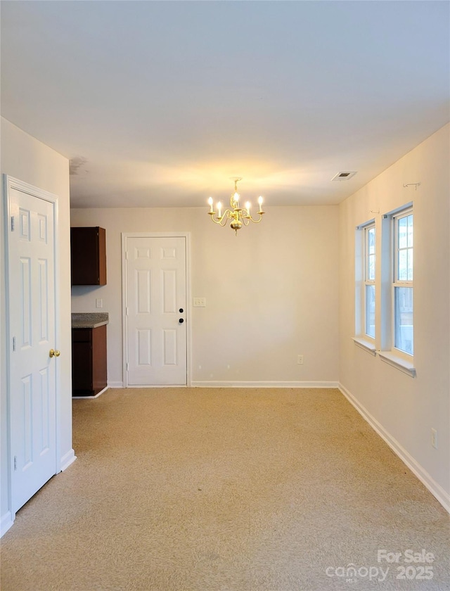 carpeted spare room with a chandelier