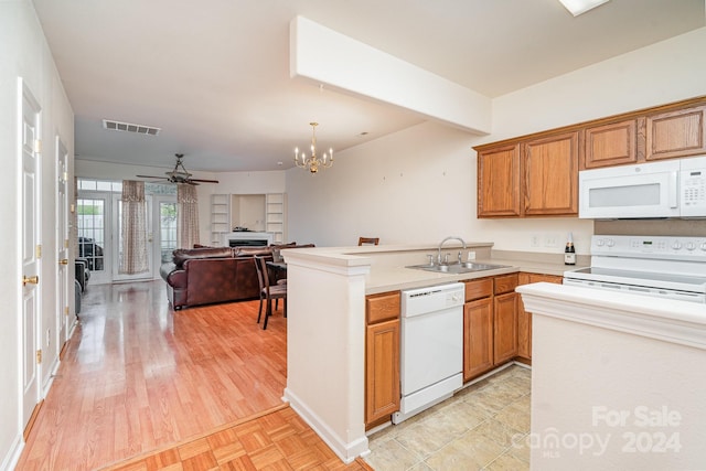 kitchen with light wood-type flooring, white appliances, sink, and kitchen peninsula