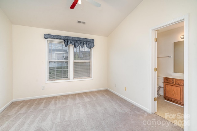 unfurnished bedroom featuring light carpet, connected bathroom, vaulted ceiling, and ceiling fan