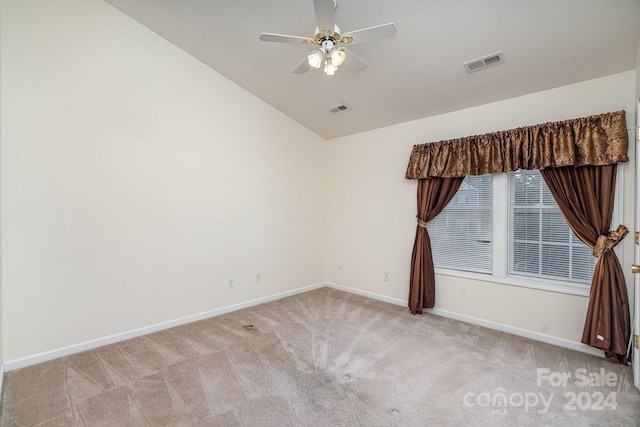 spare room featuring lofted ceiling, ceiling fan, and light carpet