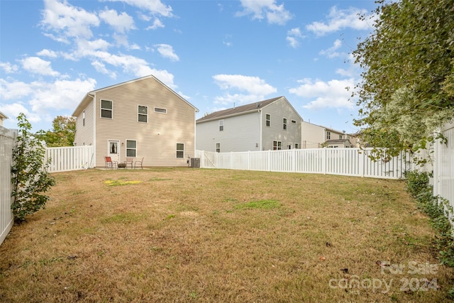 back of property featuring a yard and central AC