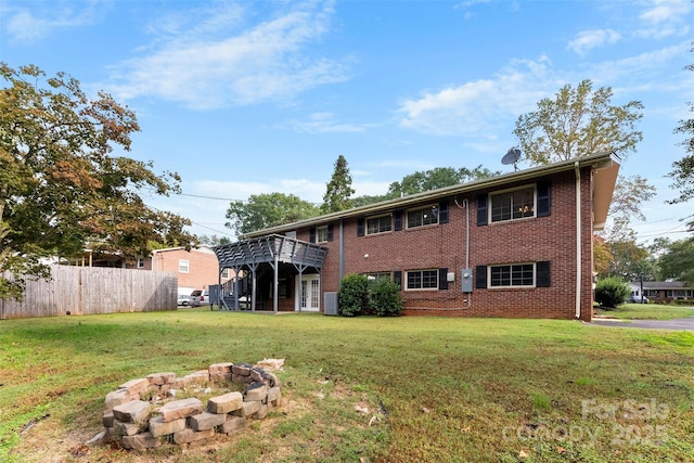 back of house with a wooden deck, a yard, and a fire pit