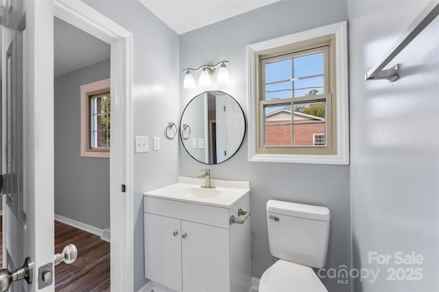 bathroom featuring vanity, wood-type flooring, a healthy amount of sunlight, and toilet