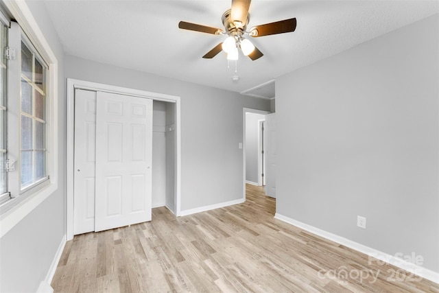 unfurnished bedroom with light wood-type flooring, a textured ceiling, ceiling fan, and a closet