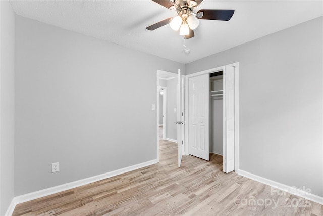 unfurnished bedroom featuring ceiling fan, a textured ceiling, a closet, and light wood-type flooring