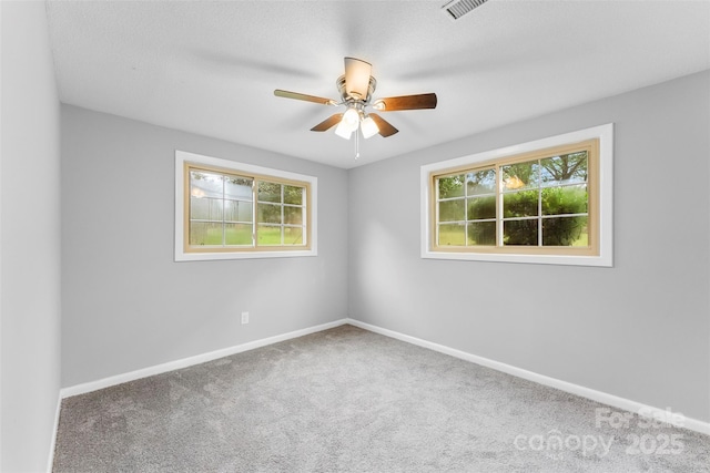 carpeted spare room featuring ceiling fan and a wealth of natural light