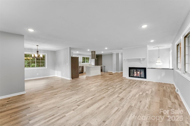 unfurnished living room with an inviting chandelier and light hardwood / wood-style floors