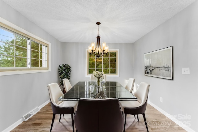 dining space with hardwood / wood-style floors, a textured ceiling, and a chandelier