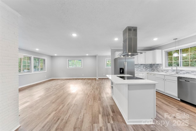 kitchen featuring hanging light fixtures, stainless steel appliances, island range hood, white cabinets, and a kitchen island