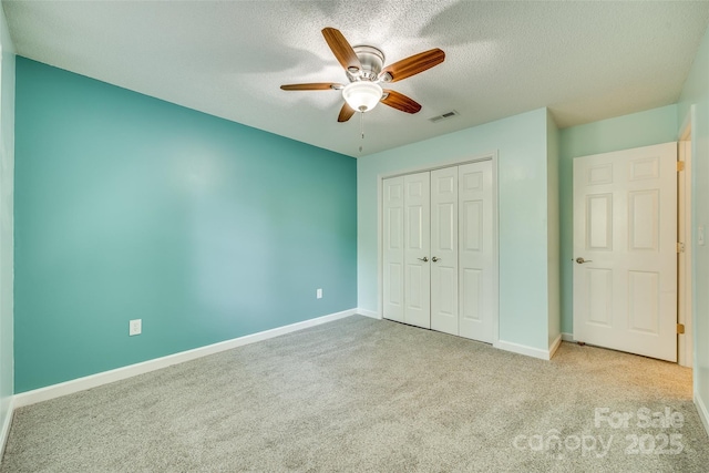 unfurnished bedroom featuring a textured ceiling, ceiling fan, light carpet, and a closet