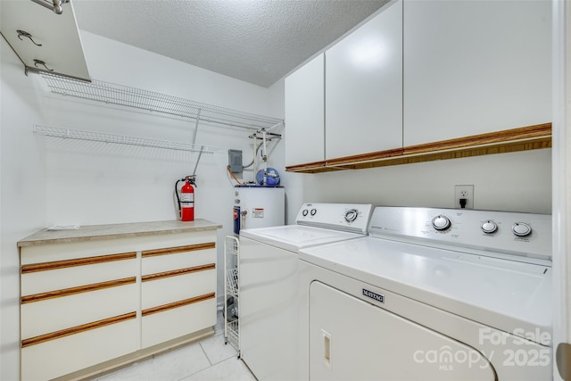 laundry area with washing machine and clothes dryer, light tile patterned floors, cabinets, and a textured ceiling