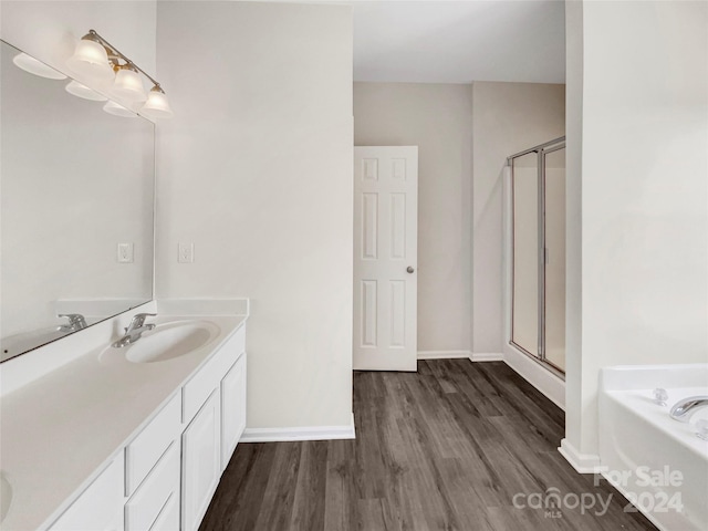 bathroom with plus walk in shower, hardwood / wood-style floors, and vanity