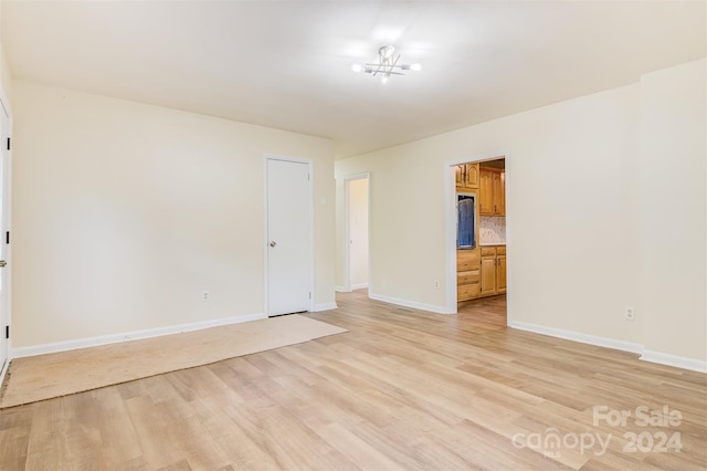 empty room with an inviting chandelier and light hardwood / wood-style floors