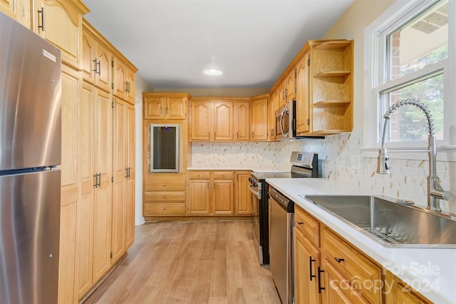 kitchen featuring light hardwood / wood-style flooring, stainless steel appliances, decorative backsplash, and sink