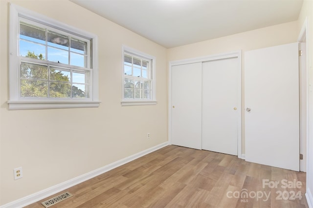 unfurnished bedroom with light hardwood / wood-style flooring and a closet