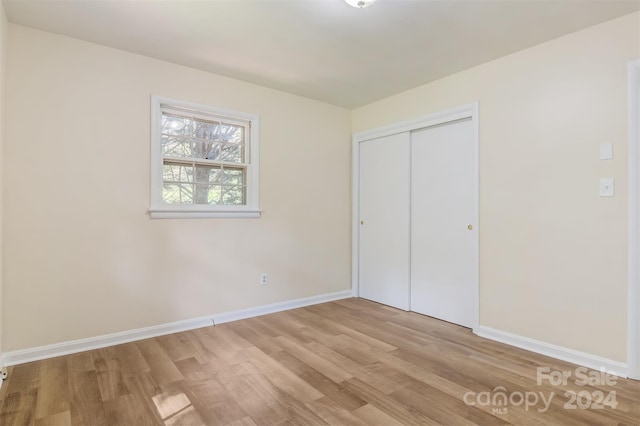 unfurnished bedroom with a closet and light hardwood / wood-style floors