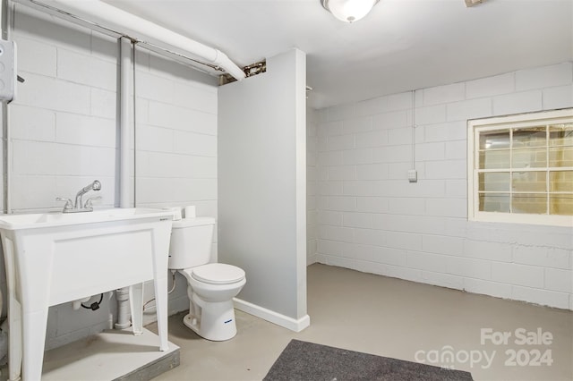 bathroom with concrete flooring, a shower, and toilet