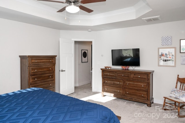 carpeted bedroom with ceiling fan and a tray ceiling