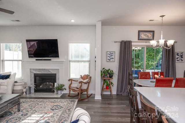 living room featuring a high end fireplace, a chandelier, and dark hardwood / wood-style flooring